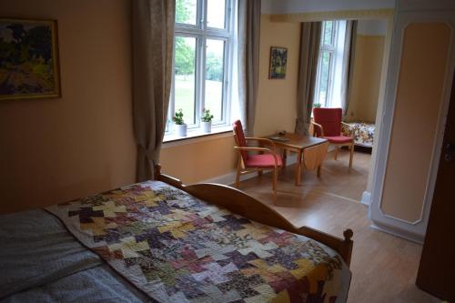 a bedroom with a bed and a table and windows at Nygammelsø Bed & Breakfast in Stege