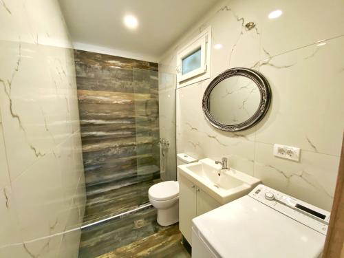 een badkamer met een toilet, een wastafel en een spiegel bij MG House with Sea and Garden view in Korakiaí