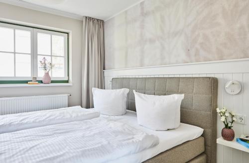 a bedroom with a bed with white sheets and pillows at Villa Fortuna in Ostseebad Sellin