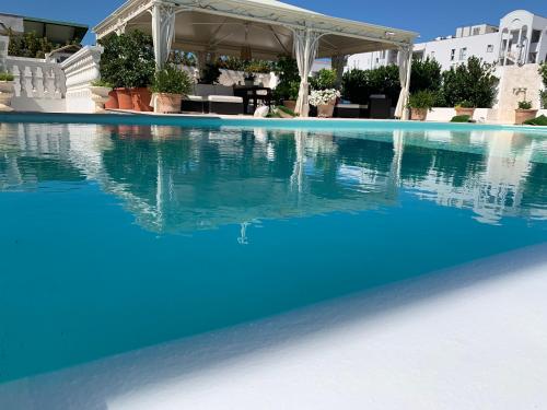 a swimming pool with blue water and a gazebo at White House Luxury Hospitality in Olbia