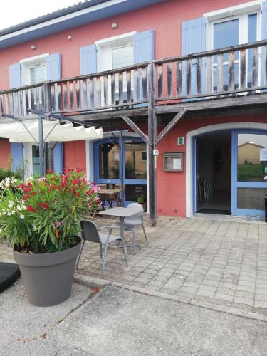 a patio with a table and chairs in front of a building at Hôtel Rose des Vents in Baix
