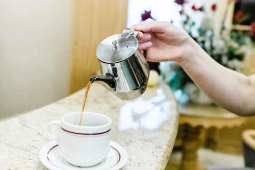 een persoon die koffie in een kopje giet op een tafel bij The Nayland Hotel in Londen