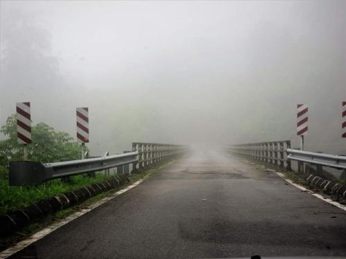 a misty road with a bridge in the fog at FH Comfy Home in Bukit Fraser