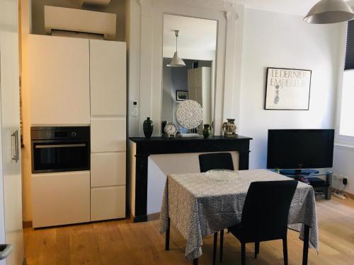 a kitchen with a table with chairs and a television at Joli et agréable studio in Bordeaux