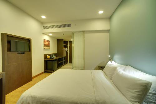 1 dormitorio con 1 cama blanca grande y TV en Keys Select by Lemon Tree Hotels, Kochi, en Kochi