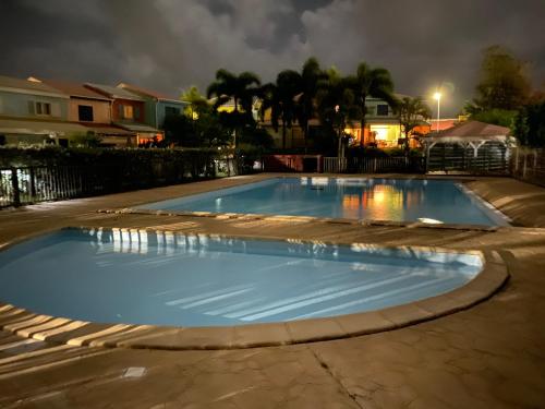 une piscine dans une cour la nuit dans l'établissement Maison mitoyenne , piscine,Citerne, jardin, parking, plage, au Gosier