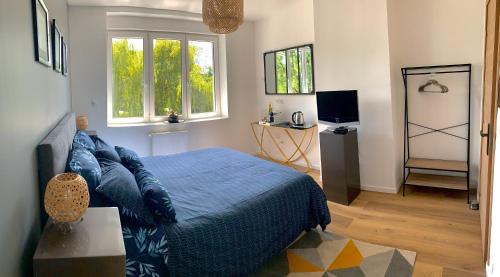 um quarto com uma cama azul e uma televisão em La Demeure Marcquoise em Marcq-en-Baroeul