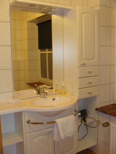 a white bathroom with a sink and a mirror at Schumacher's Landhaus - Bücherhotel in Friedeburg