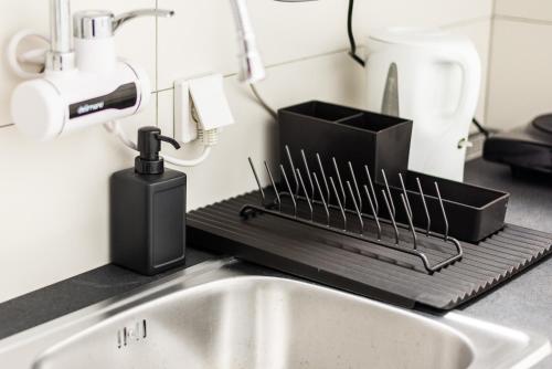 a kitchen counter with a sink and a drying rack at BLACK & YELLOW Centrally located studio in Novi Sad