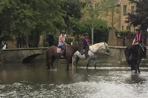 a group of people riding horses through a river at Coombe House in Bourton on the Water