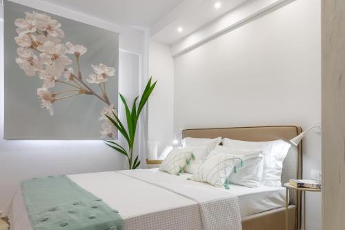 Armenos Elegance Apartments في إيريسوس: غرفة نوم بيضاء مع سرير مع وردة على الحائط