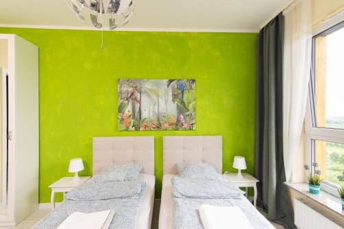 2 camas en una habitación con una pared verde en Apartament Zdrojowa 58m2, en Grójec