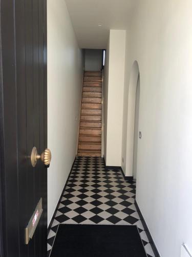 um corredor com uma porta preta e um piso xadrez em Guesthouse Gieterij em Bruges