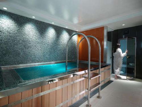 une personne debout dans une salle de bains avec piscine dans l'établissement The Athenaeum Hotel & Residences, à Londres