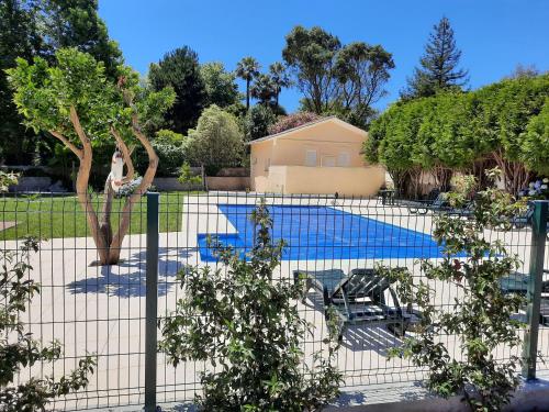a fence with a swimming pool in a yard at Metro Vilar Suites & Villas in Vilar do Pinheiro