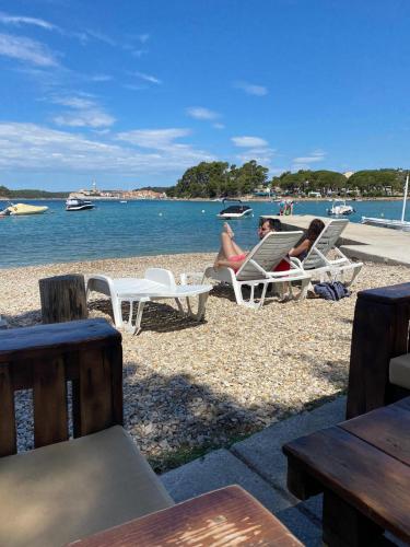 two people sitting in lawn chairs on the beach at Victoria Mobilehome in Padova Premium Camping Resort in Banjol