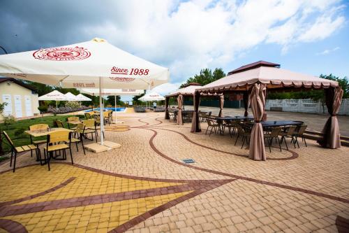 a patio with tables and chairs and umbrellas at Оазис in Zalishchyky