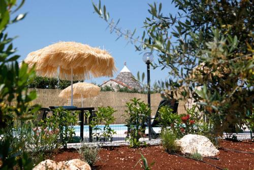 a patio with two umbrellas and a table and chairs at L'Isola Felice e Trulli Sotto Le Stelle in Castellana Grotte