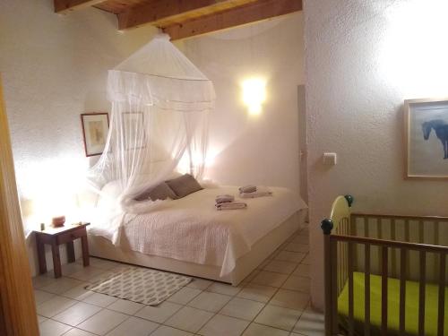 a bedroom with a white bed with a canopy at Le Mas de Baraud in Villeneuve-de-Berg