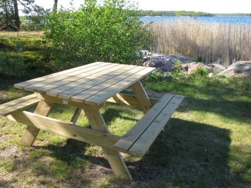 a wooden picnic table sitting on the grass near a lake at Stenslid Bottna By St Anna in Söderköping