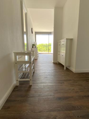 an empty room with a kitchen and a hallway with wood floors at Meeresrauschen in Laboe