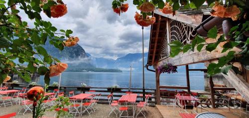 a patio with tables and chairs and a view of the water at Bräugasthof Hallstatt in Hallstatt