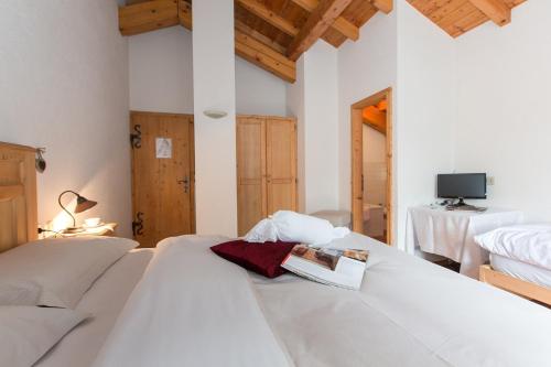 1 Schlafzimmer mit 2 weißen Betten und einem TV in der Unterkunft B&B Cecilia in Valfurva