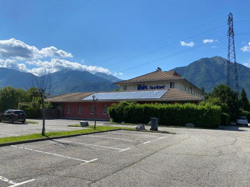a building with a parking lot with mountains in the background at ibis budget Albertville in Gilly-sur-Isère