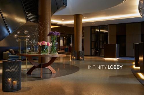 a lobby with a table with vases of flowers on it at Infinity Hotel & Conference Resort Munich in Unterschleißheim