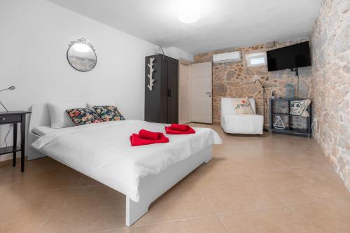 ein Schlafzimmer mit einem weißen Bett mit roten Kissen darauf in der Unterkunft Apartman Otto in Punat