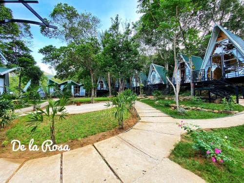 a row of cottages with trees and a walkway at Homestay De la Rosa - Côn Đảo in Con Dao