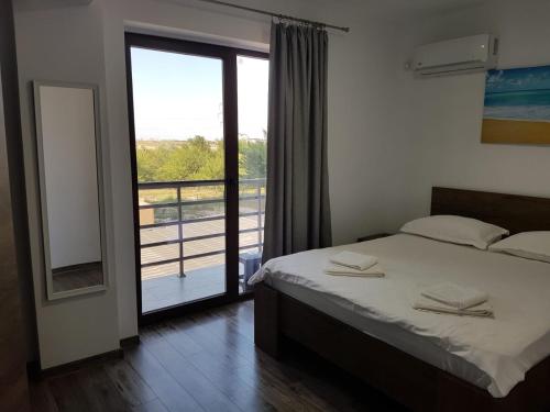 a bedroom with a bed and a view of a balcony at Vila La Matache in Eforie Nord