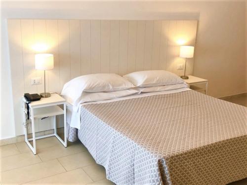 a bedroom with a bed and two tables with lamps at Hotel Villa Eleonora in Scauri