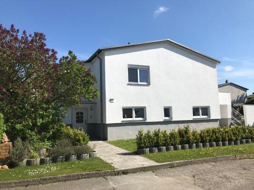 Una casa blanca con un árbol delante. en Ferienhaus Nahe der Ostsee, en Bad Doberan