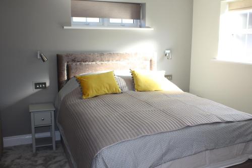 ein Schlafzimmer mit einem Bett mit zwei gelben Kissen in der Unterkunft Frinton Escapes in Frinton-on-Sea