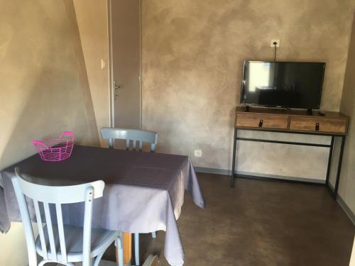 uma sala de jantar com uma mesa e uma televisão em AUX PORTES D'AUBRAC studio 2 personnes em Salgues