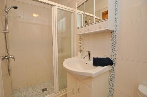 a white bathroom with a sink and a shower at Tenis Golf Mar by OCvillas in Quarteira