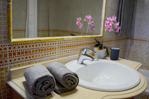ein Badezimmer mit einem Waschbecken, einem Spiegel und Handtüchern in der Unterkunft VILA CRISTINA MAR (8 guests and oceanview) in Albufeira