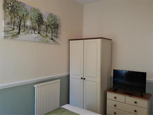 a bedroom with a bed and a cabinet and a tv at Ashfields in Llandudno