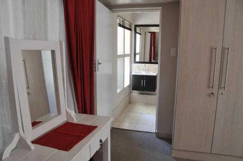 a bathroom with a mirror and a red shower curtain at A&A Guesthouse in Port Elizabeth