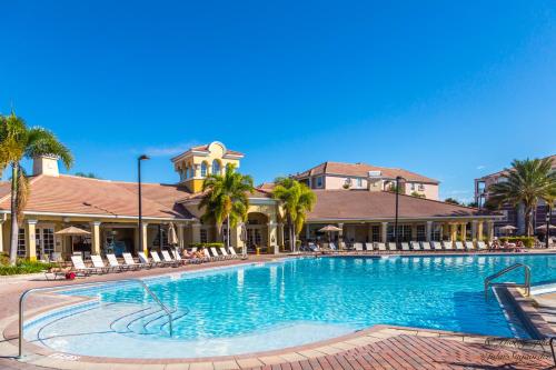 - une piscine dans un complexe avec des chaises et des palmiers dans l'établissement Luxury ! Vista Cay Lake View Joy - Next to Pool Near Parks & OCCC, à Orlando