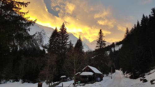a cabin in the snow with a sunset in the background at Houghton Haus in Mallnitz