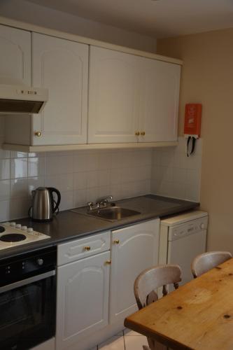 a kitchen with white cabinets and a wooden table at Killarney Country Club in Faha