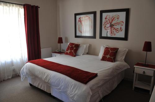a bedroom with a large white bed with red pillows at A&A Guesthouse in Port Elizabeth