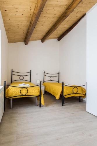 two beds in a room with a wooden ceiling at La casa del tenore in Recanati