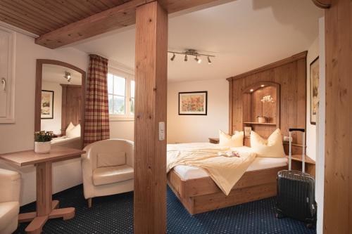 a bedroom with a bed and a desk and a chair at Hotel-Gasthof Der Wiesengrund in Bad Hindelang