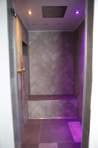 a walk in shower with purple lighting in a bathroom at Rooftop Moselsuite in Cochem