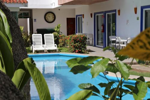 a swimming pool with chairs and a clock on the wall at Hotel Alikar in Santa Cruz Huatulco