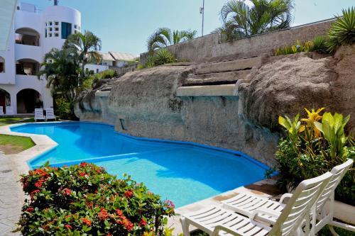 a swimming pool with two lawn chairs and flowers at Hotel Alikar in Santa Cruz Huatulco