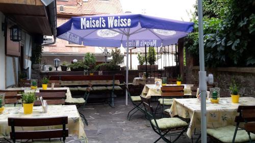 an outdoor restaurant with tables and a blue umbrella at Zum Burgtörle in Walldürn